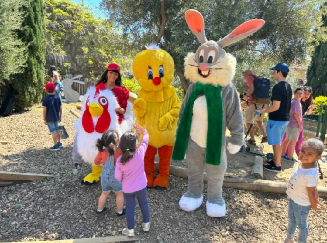 Mascottes poule et poussin avec lapin, entourées d'enfants
