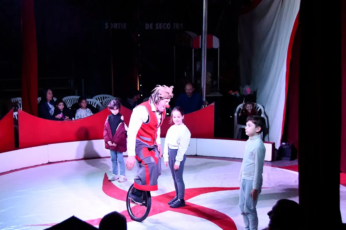 Clown en monocycle entouré de jeunes spectateurs
