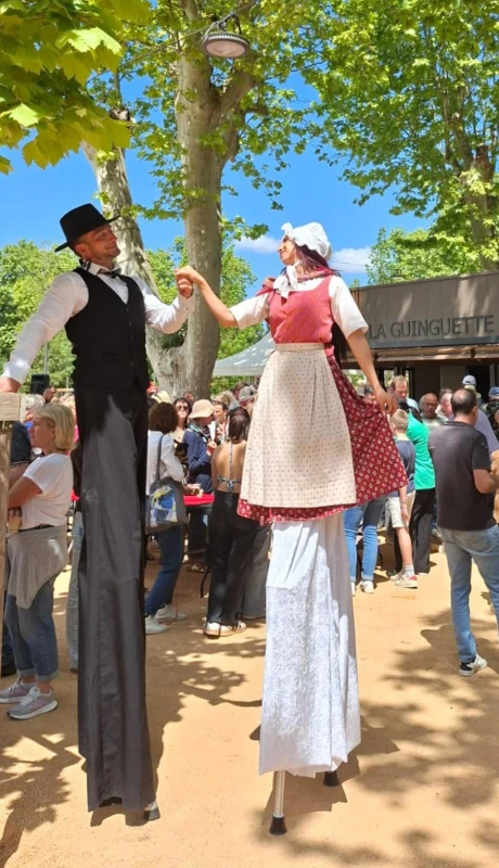 Couple d'échassiers en costumes provençaux d'époque dans une fête de village