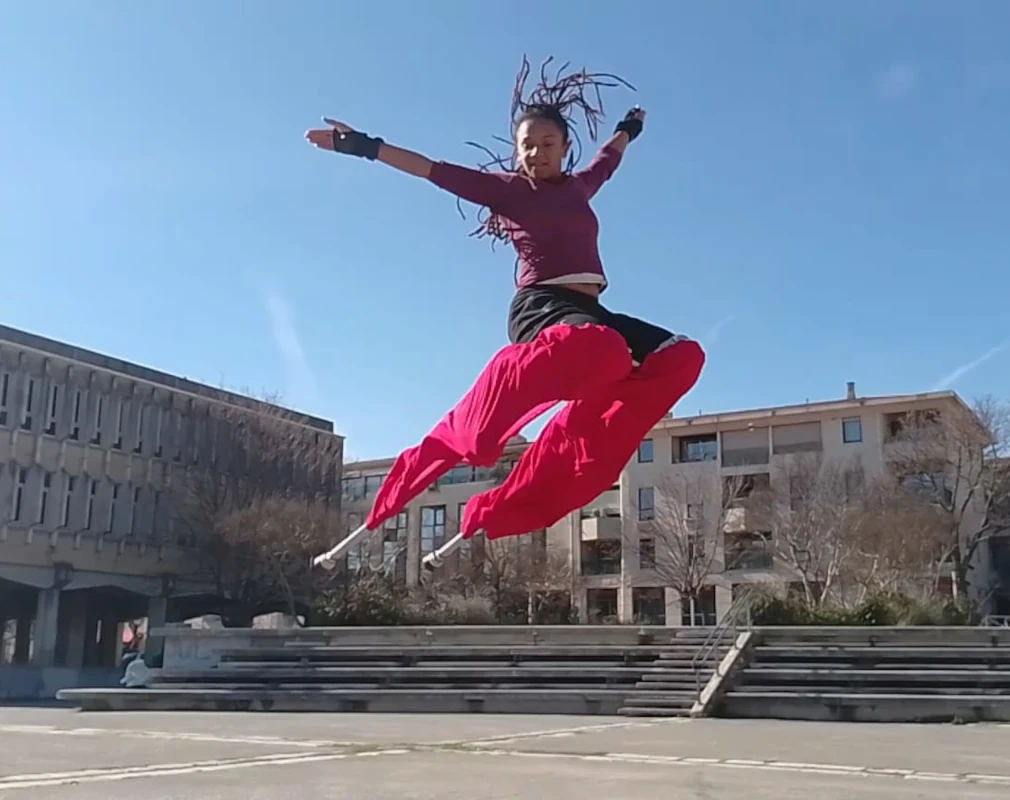 Échassière en pantalon rouge réalisant un grand saut