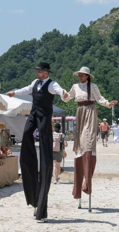 Couple d'échassiers en costumes d'époque, marché d'été en montagne