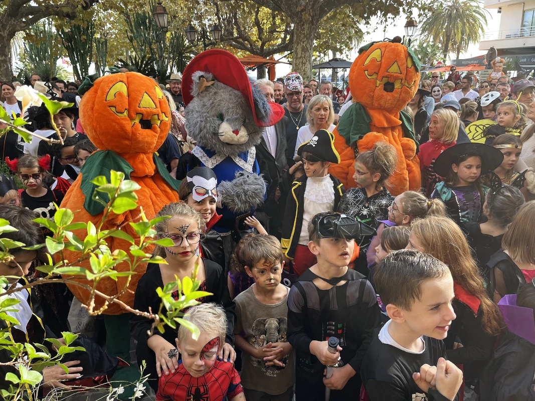 Mascottes citrouilles et souris géante entourées d'enfants costumés