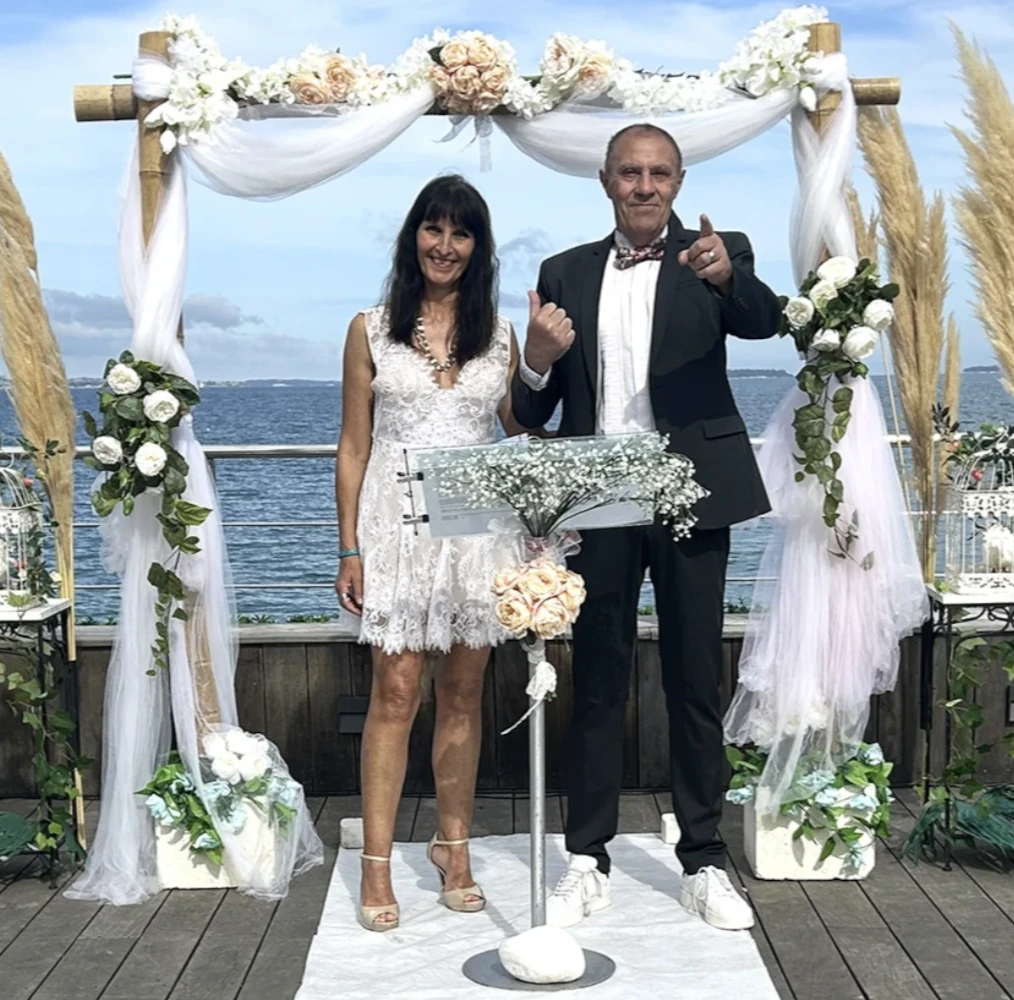 Cérémonie de mariage en bord de mer, les mariés sous l'arche fleurie