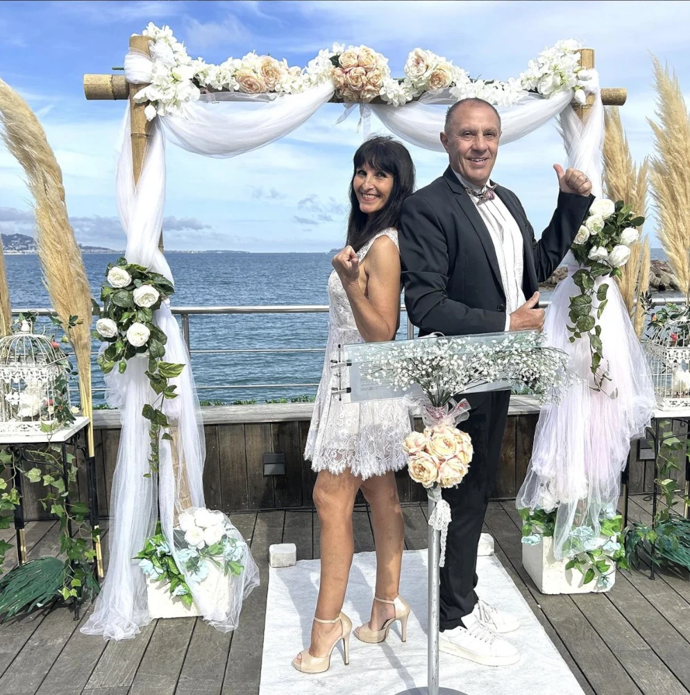 Mariés posant dos à dos devant la mer