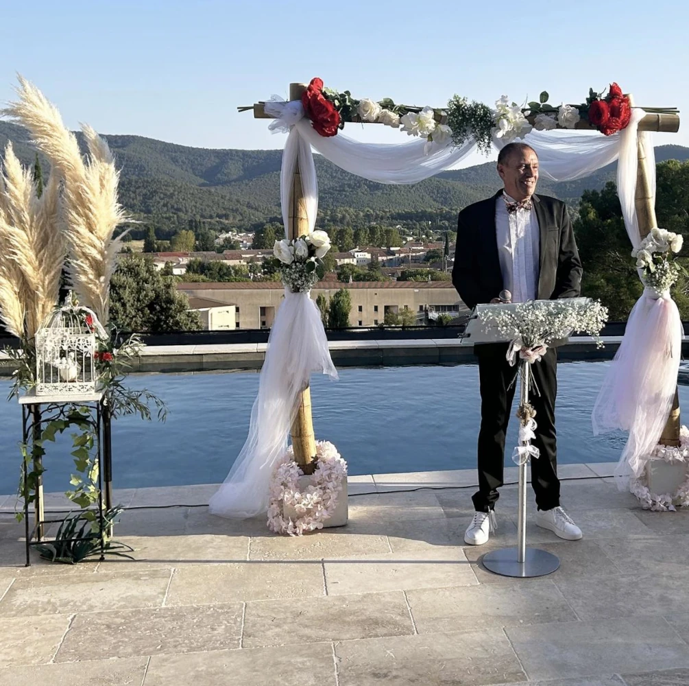 Cérémonie de mariage avec vue sur les collines, arche de roses rouges et blanches