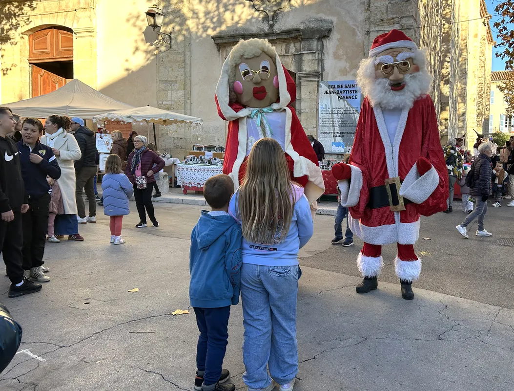 Père Noël et Mère Noël géants devant une église, marché de Noël