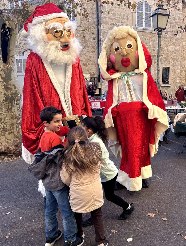Père Noël et Mère Noël géants entourés d'enfants