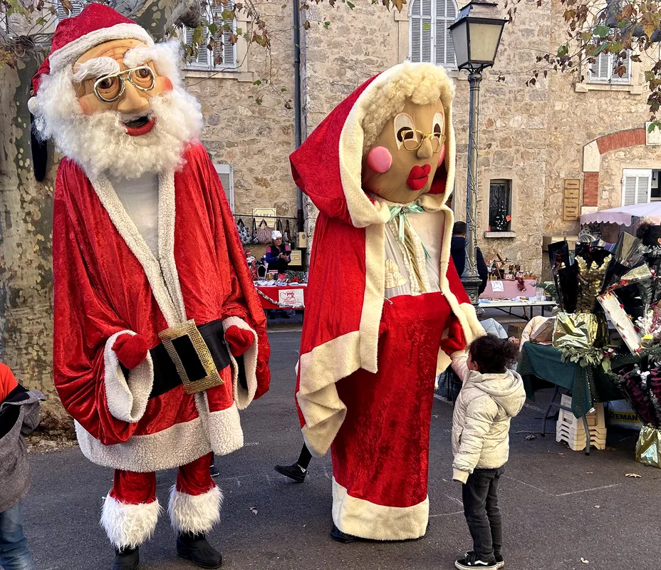 Père Noël et Mère Noël géants dans une rue de village provençal