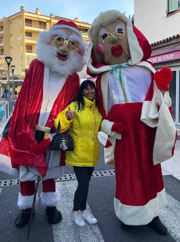 Père Noël et Mère Noël géants posant avec une visiteuse