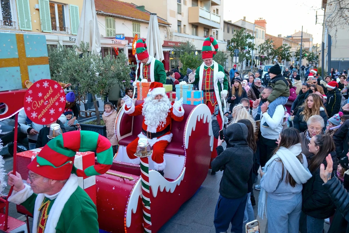 Traîneau du Père Noël entouré d'elfes, parade dans la rue