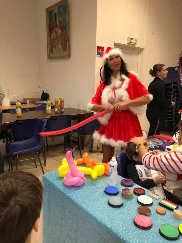 Mère Noël réalisant du maquillage et des sculptures de ballons pour des enfants