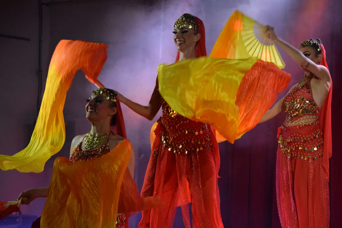 Revue de danseuses en costumes à voiles orange et rouges, thème Bollywood