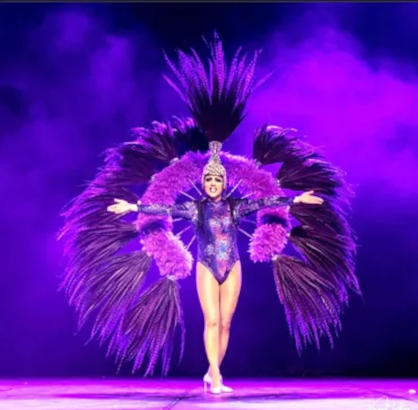 Transformiste en costume de plumes violettes, bras ouverts