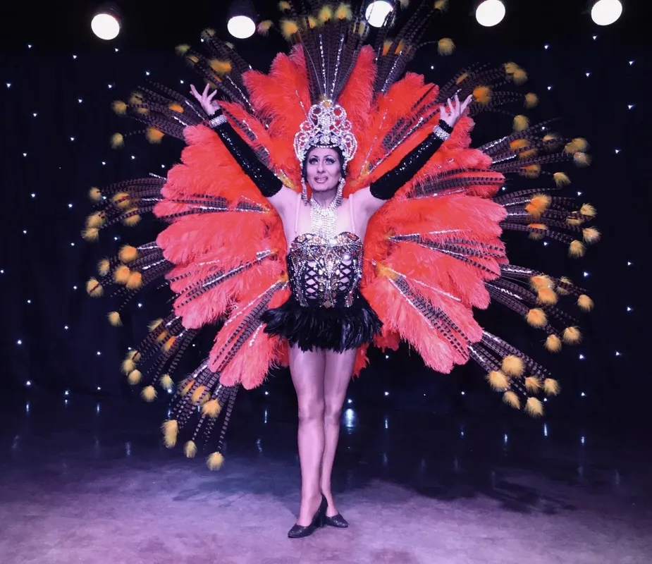 Transformiste en costume de plumes rouges, bras ouverts