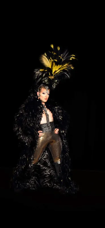 Transformiste en costume de plumes noires et dorées