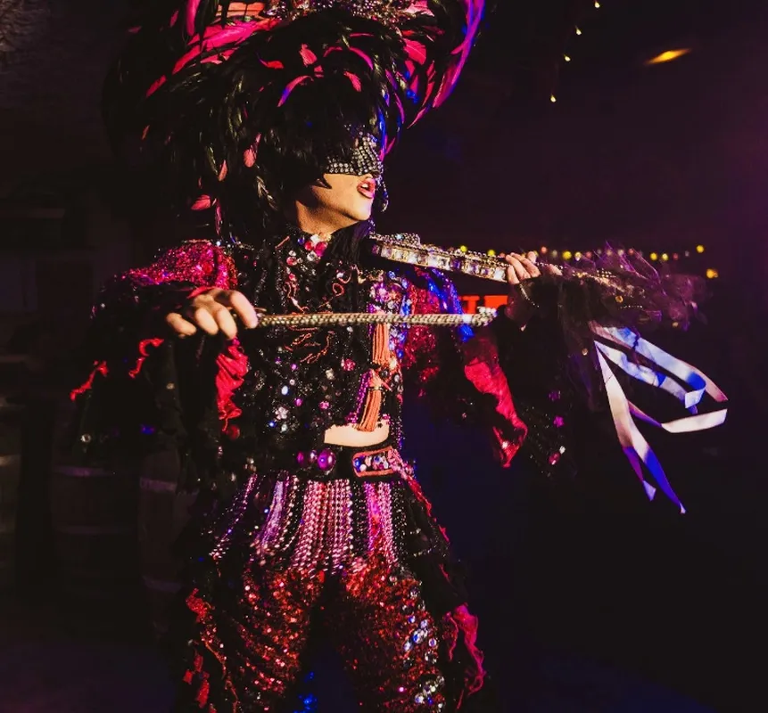 Transformiste masqué en costume rouge et noir avec éventails