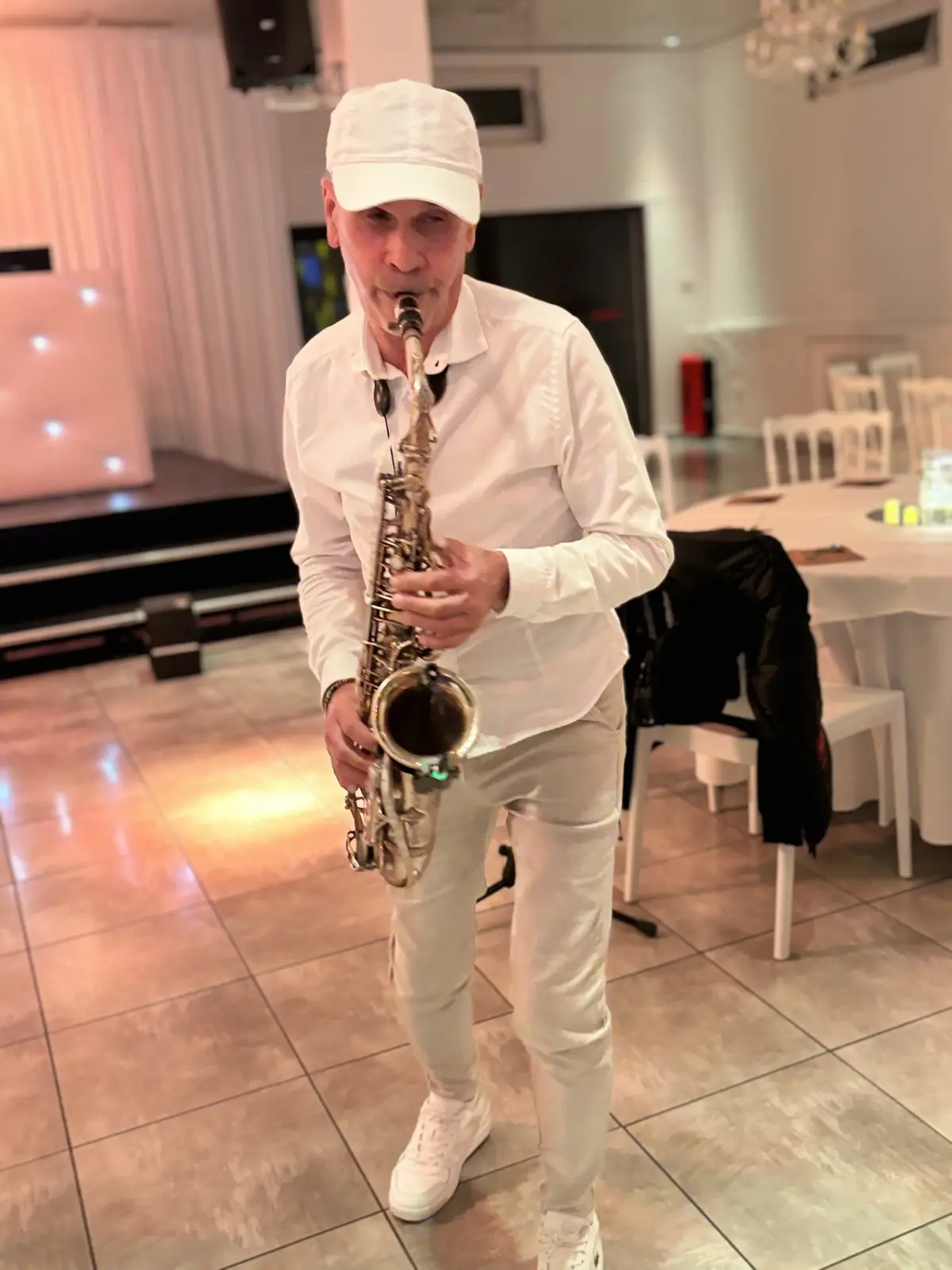 Saxophoniste en tenue blanche sur la piste de danse d'une salle de réception