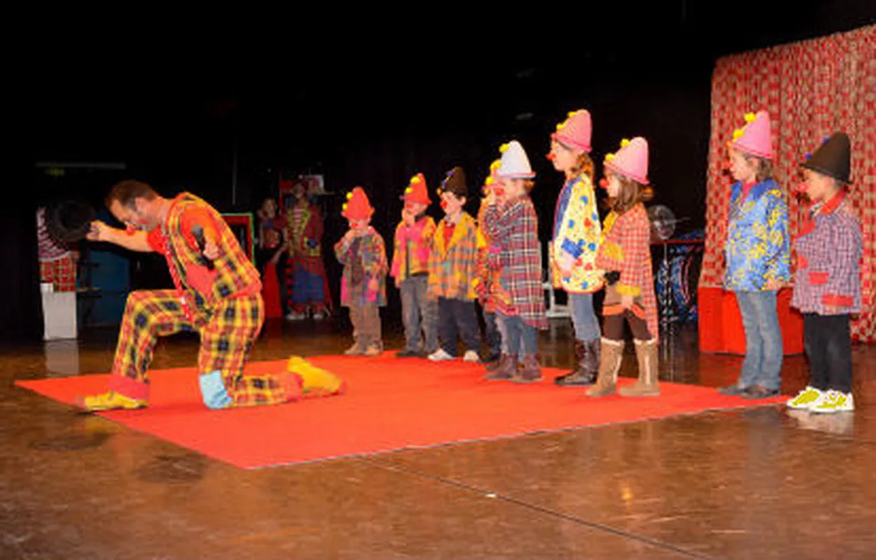 Clown en spectacle avec un groupe d'enfants costumés sur scène